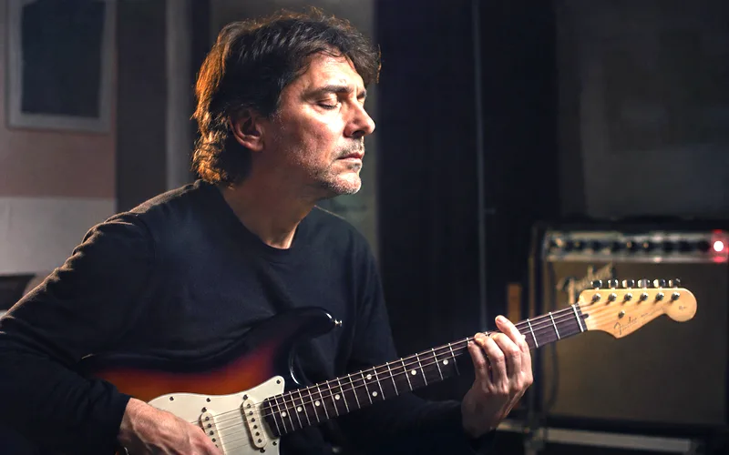 Guitarist with eyes closed listening closely while playing a single note on an electric guitar
