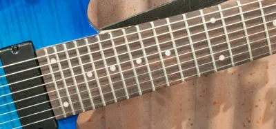 Close up of an 8 string electric guitar fretboard and strings