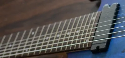 Headstock and neck of an 8 string electric guitar showing extended scale length