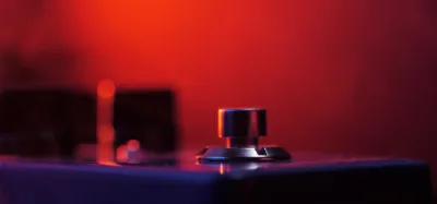 Guitar compressor pedal on a pedalboard with knobs for level and sustain