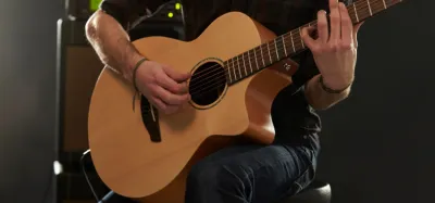 Nine-volt battery being changed in the back of an acoustic-electric guitar