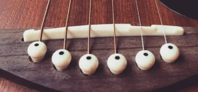 Acoustic guitar bridge with the saddle visible, used to explain saddle fit and replacement