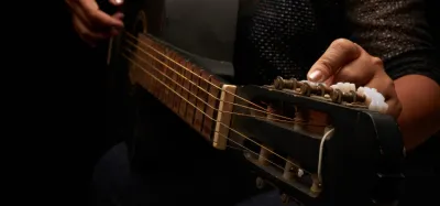 Guitarist adjusting tuning pegs to set an alternate guitar tuning