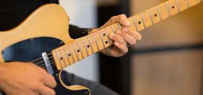 Hand pressing strings on an electric guitar fretboard to show finger comfort