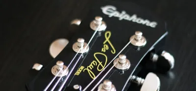 Epiphone acoustic guitar resting against an amp in a home studio