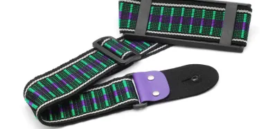 Guitar strap attached to an electric guitar resting against an amp