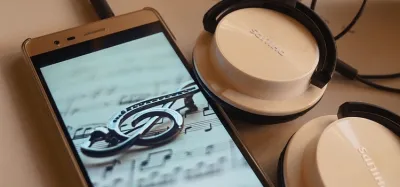 Smartphone running a guitar tuner app next to an acoustic guitar
