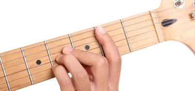 Hand fretting a B major chord on an acoustic guitar neck