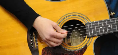 Beginner guitarist learning easy songs on an acoustic guitar