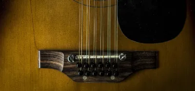 A 12-string acoustic guitar resting against an amp