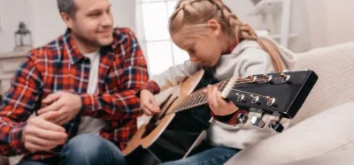 A child learning to play a small 3/4-size acoustic guitar