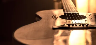 Acoustic guitar with several brands of strings laid out for comparison