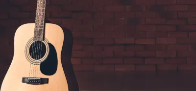 Beginner acoustic guitar with starter accessories on a wood floor