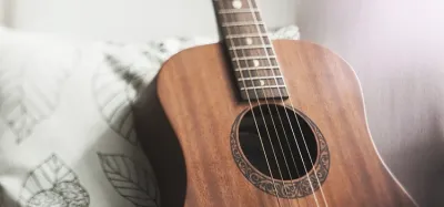 Several affordable acoustic guitars under $300 lined up against a wall