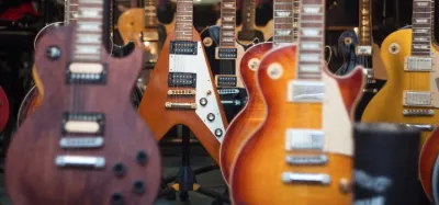 Row of electric guitars including a Stratocaster and Les Paul on stands