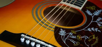 Epiphone acoustic guitar resting against an amp in a studio