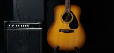 Small acoustic guitar amp on a wood floor next to an acoustic-electric guitar