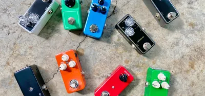 Small mini compressor pedals lined up on a guitar pedalboard