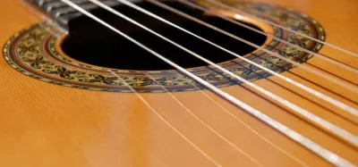 Nylon string travel guitar resting against a backpack ready for the road
