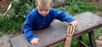 Young child holding a small acoustic guitar during an early learning session