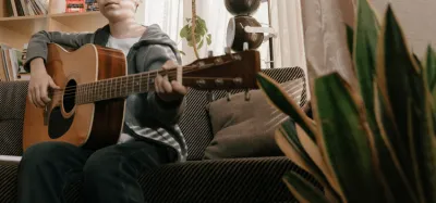 Guitarist with small hands fretting chords on a thin-neck guitar