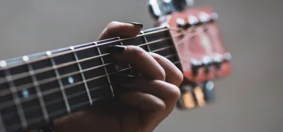Person learning guitar at home using the Yousician app on a tablet