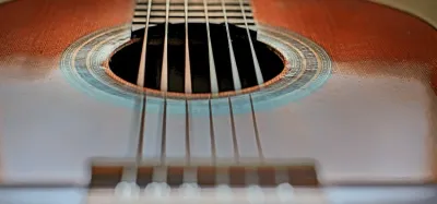 Close-up of nylon guitar strings being fitted to a steel string acoustic guitar