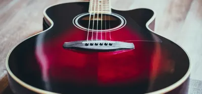 Close-up of an acoustic guitar bridge, saddle, and pin holes during a repair
