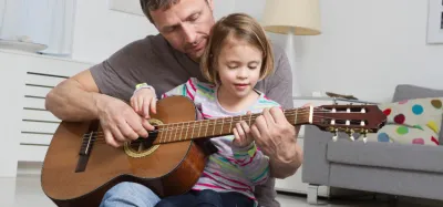 Young child learning to play beginner songs on an acoustic guitar