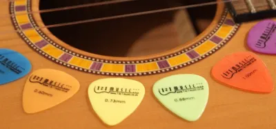 Different sized guitar picks arranged from thin to thick gauges