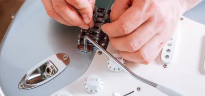 Guitarist performing a do-it-yourself repair on an electric guitar