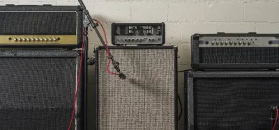 Guitar amp head sitting on a speaker cabinet next to a combo amp