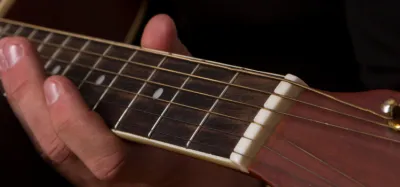 Coiled guitar strings next to a guitar headstock and tuning pegs