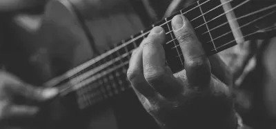 Close-up of a hand fretting chords on a guitar neck