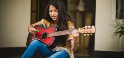 Girl learning to play beginner guitar songs without barre chords