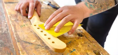 Guitar neck being refinished with a hand-rubbed tung oil coat