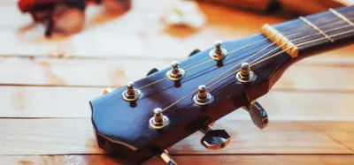 Close-up of a guitar nut with strings seated in the slots being lubricated