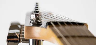 Close-up of a guitar nut at the top of the fretboard guiding the strings