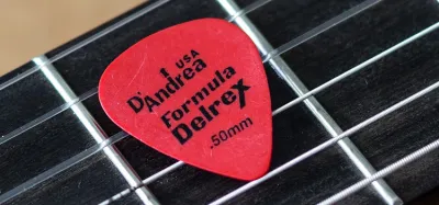 Assorted guitar picks of different thicknesses fanned out on a table