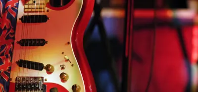 Close-up of electric guitar pickups being adjusted with a screwdriver