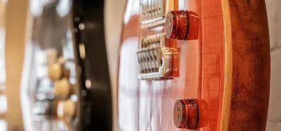 Several guitars hanging on a wall from wall-mounted guitar hangers
