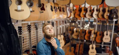 Acoustic guitar resting against a wall representing different price levels