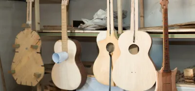Partly assembled guitar body and neck on a workbench surrounded by luthier tools