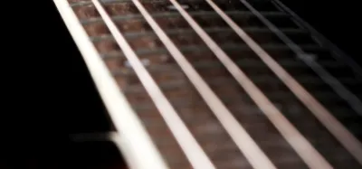 Adjusting the saddle on an acoustic guitar bridge to lower the action