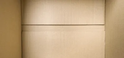 A guitar packed with cushioning inside a corrugated cardboard shipping box without a case
