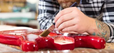 An electric guitar body being refinished and painted on a workbench