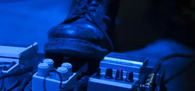 Digital delay pedal on a guitar pedalboard with the level, time, and feedback knobs visible