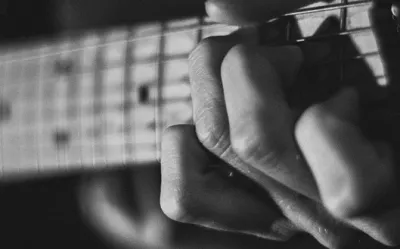 Close-up of a beginner's fingers pressing strings on a guitar fretboard
