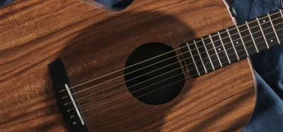 Reddish koa wood acoustic guitar with figured grain top