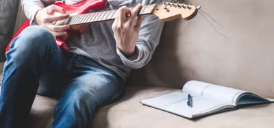 Beginner learning guitar from an open song book